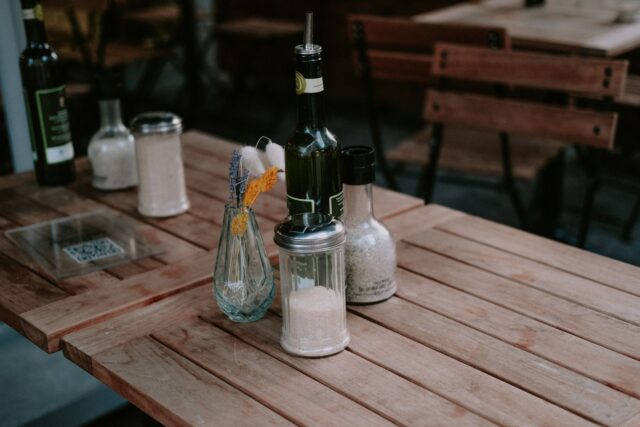 Masă de restaurant cu un preparat servit elegant, un pahar cu apă și un meniu închis